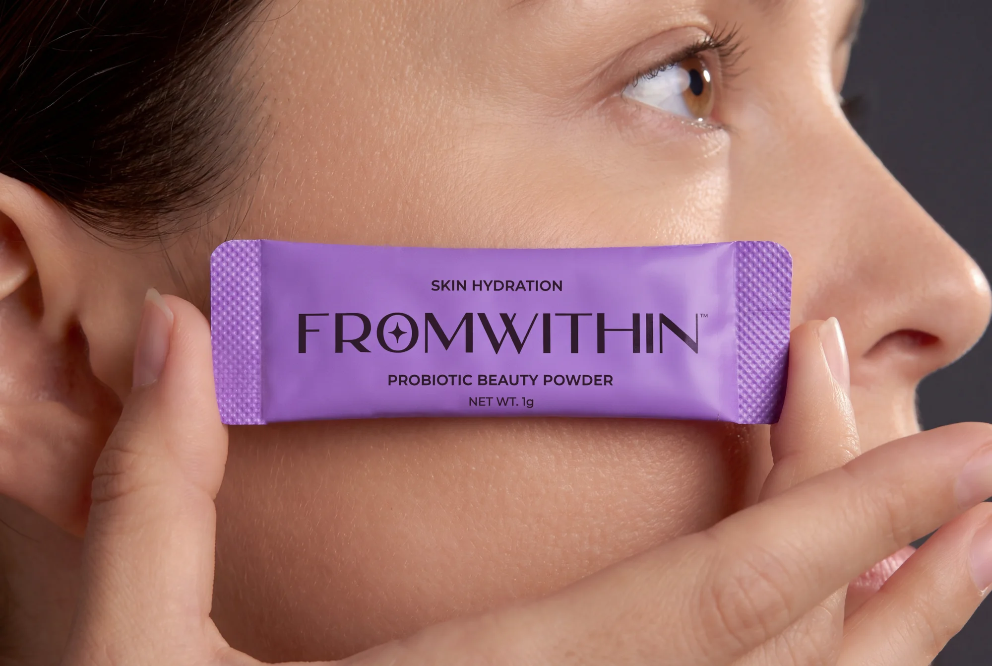 A FROMWITHIN sachet held against the cheek